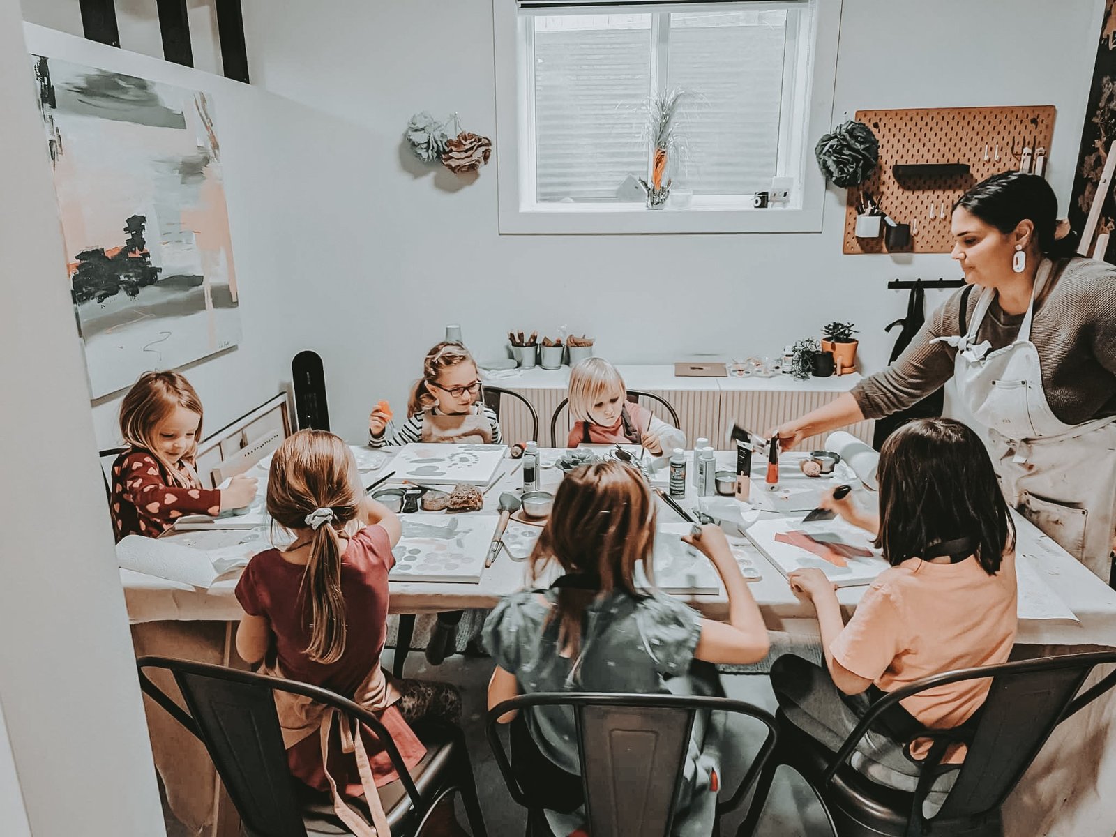 Leta Taylor teaching a class of five children at the studio table at Painting Prodigies